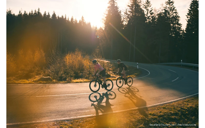Two racing cyclists at sunrise on a sepentine