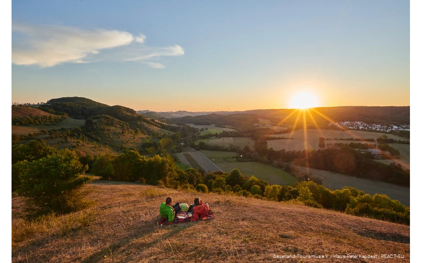 Ein Pärchen genießt den Sonnenuntergang mit Blick auf Marsberg.