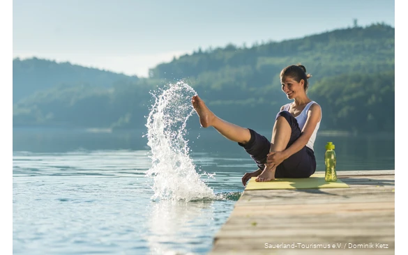 A woman sits on a jetty on the Hennesee and splashes with water.