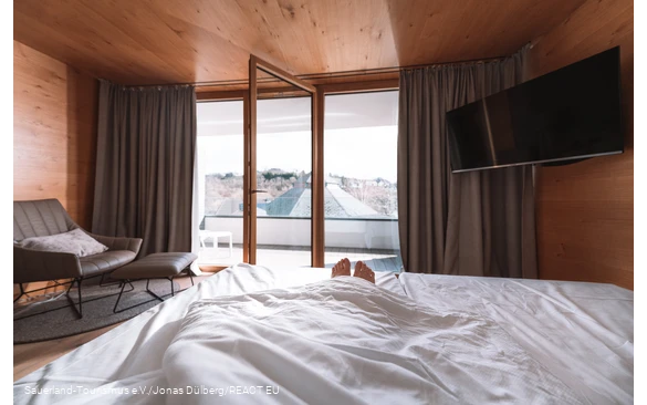 Aus einem Bett mit einem offenen Fenster schauen nur die Füße