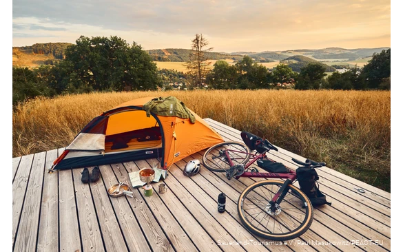 Gravel bike and tent on a trekking platform with a view over the Sauerland landscape