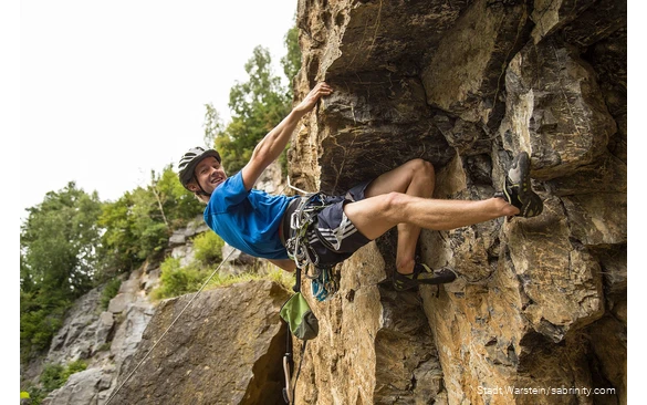 Een jonge klimmer hangt in de rotswand.