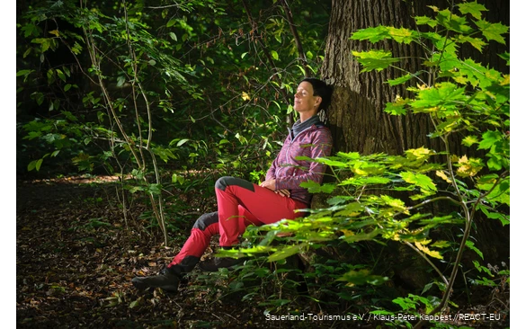 Eine Frau lässt beim Waldbaden die Natur auf sich wirken.