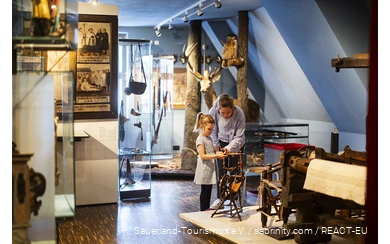 Eine Mutter und ihre Tochter betrachten eine Spindel im Südsauerlandmuseum in Attendorn.