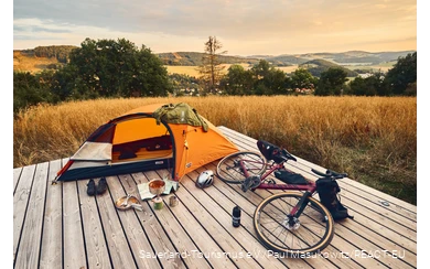 Gravel bike and tent on a trekking platform with a view over the Sauerland landscape