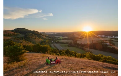 Ein Pärchen genießt den Sonnenuntergang mit Blick auf Marsberg.