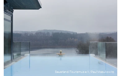 A woman relaxes in the infinity pool of a hotel.