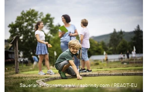 Eine Familie beim Minigolfen am Diemelsee. Ein Sohn bereitet seinen nächsten Schlag vor.