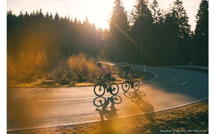Zwei Rennradfahrer bei Sonnenaufgang auf einer Sepentine