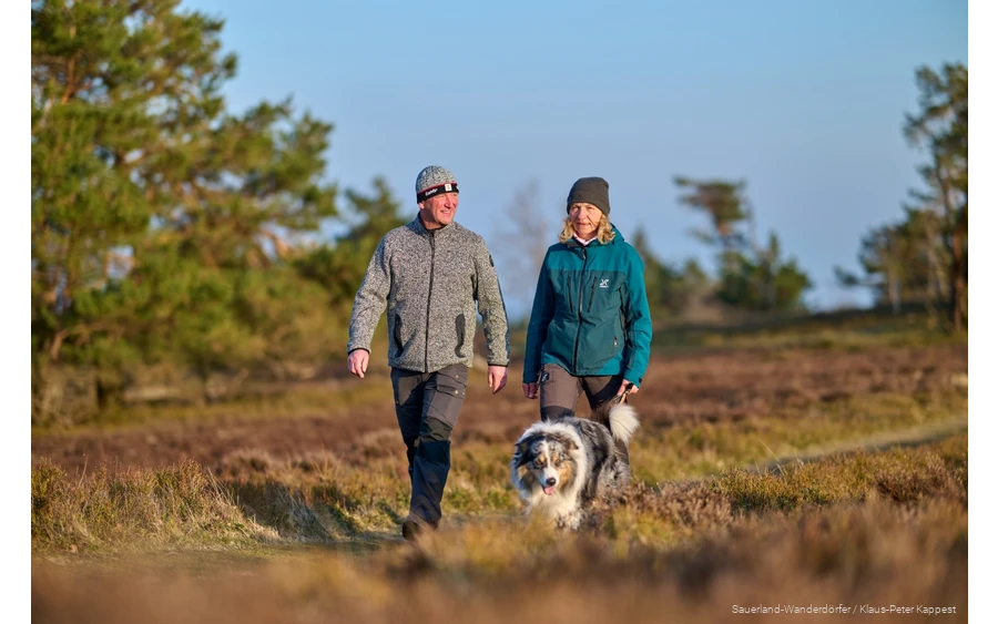 Pärchen wandert mit ihrem Hund im Winter über die Kahle Pön. Die Wintersonne scheint leicht.