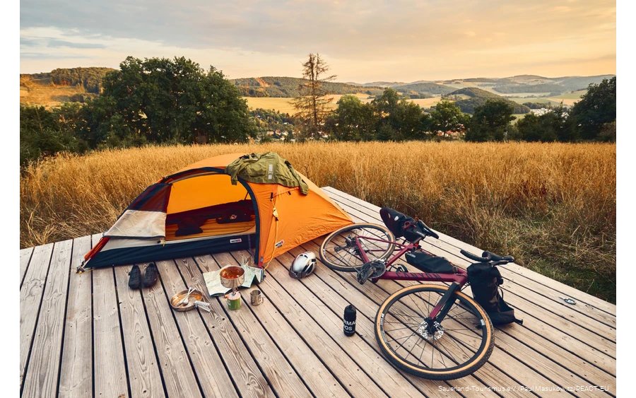 Gravelbike und Zelt auf einer Trekkingplattform mit Blick über die Landschaft des Sauerlandes