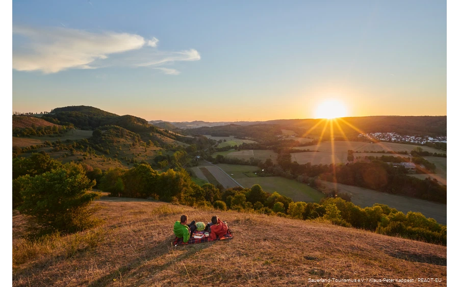 Ein Pärchen genießt den Sonnenuntergang mit Blick auf Marsberg.