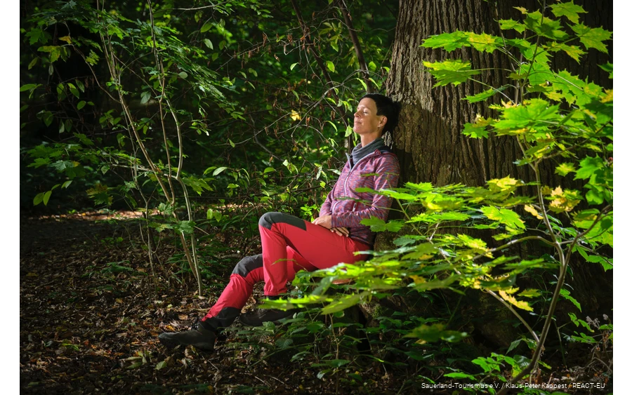 Eine Frau lässt beim Waldbaden die Natur auf sich wirken.