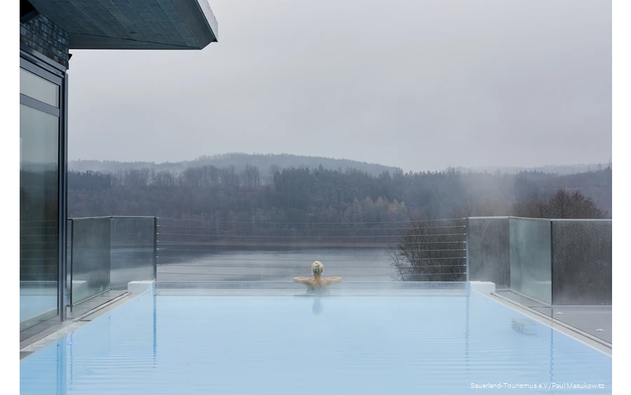Eine Frau entspannt im Infinity-Pool eines Hotels.