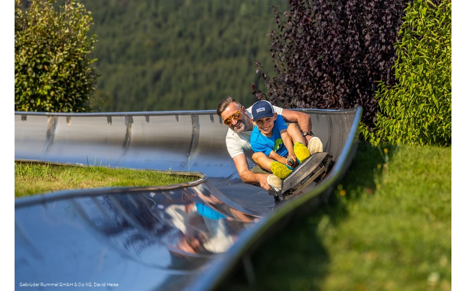 Mann und Junge auf der Sommerrodelbahn