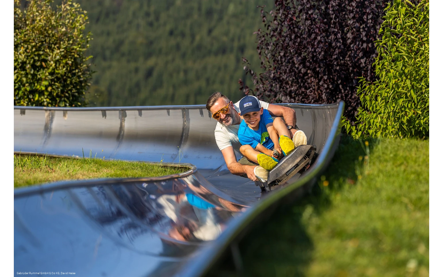 Mann und Junge auf der Sommerrodelbahn