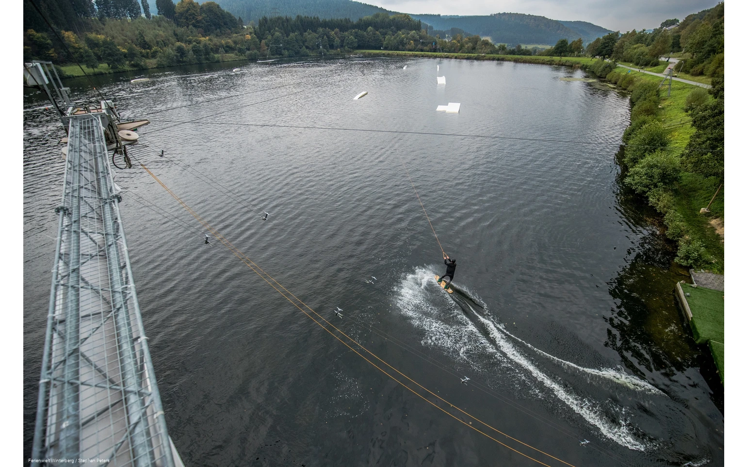 Ein Wasserskifahrer wird an einem Seil über den See gezogen.