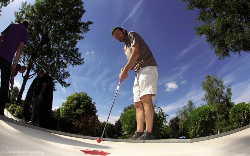Ein Mann beim Minigolf spielen.