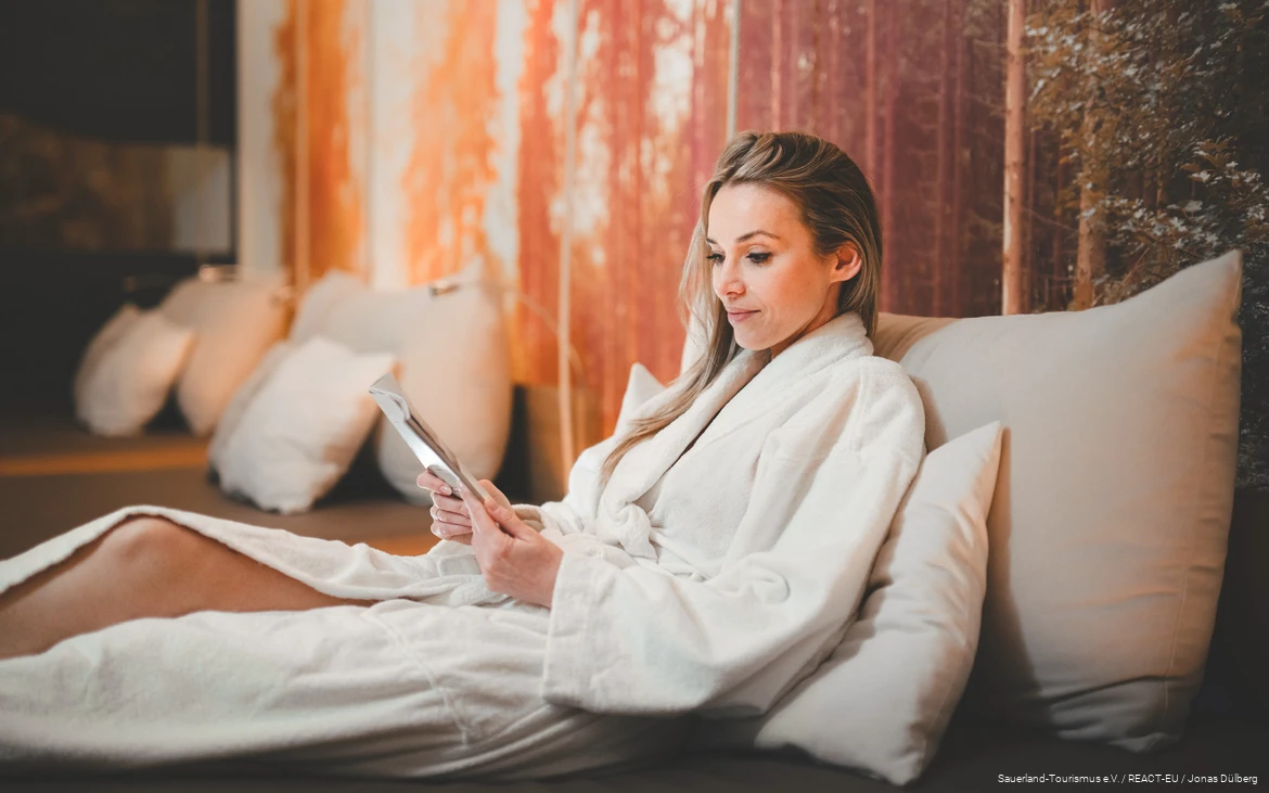 Wellness-Auszeit Frau im Bademantel liest eine Zeitschrift und entspannt.