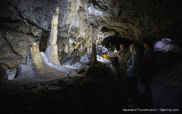 The cave guide lights up a stalactite with a flashlight.