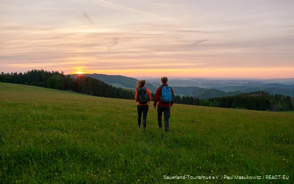 Ein Pärchen wandert in den Sonnenuntergang.