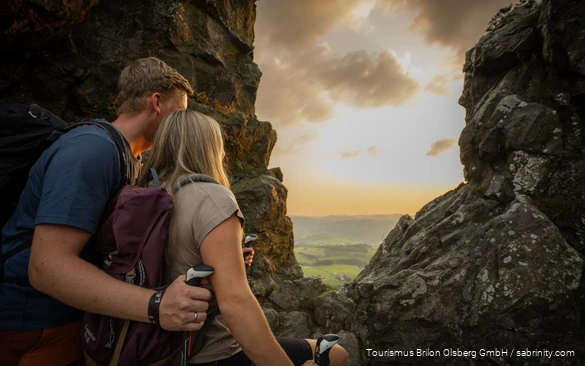 Ein Wanderpaar genießt den Ausblick von den Bruchhauser Steinen bei Sonnenuntergang.