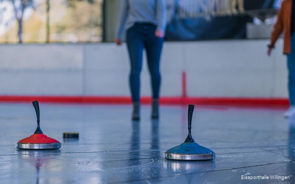 Close-up of two ice sticks, one red and one blue, on the ice.