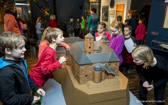 Besucher des Südsauerlandmuseums erforschen ein Modell der Waldenburg.