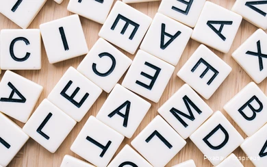 Verspreid op een tafel liggen verschillende spelstenen met letters.