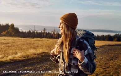 A woman in a cap enjoys the sunrise on the Kahler Asten and gazes into the distance