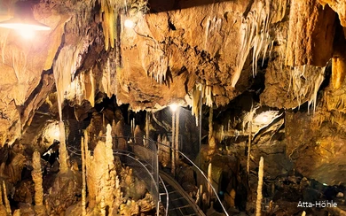 Einblick in die Atta-Höhle mit Stalaktiten und Stalakmiten und einem Gang, der zwischen ihnen durchführt.