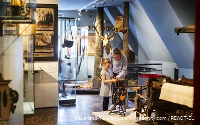 A mother and her daughter look at a spindle in the Südsauerlandmuseum in Attendorn.