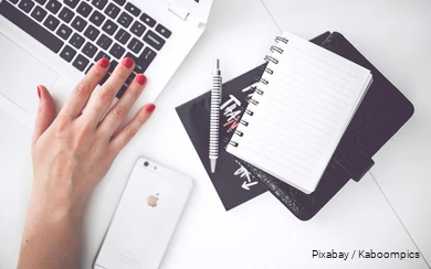 Ein Schreibtisch mit Laptop, Smartphone und Notizbuch.