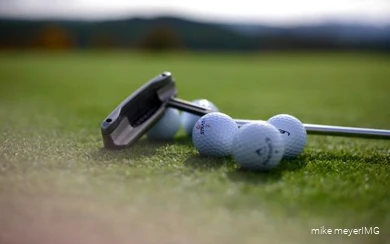 Golf clubs and golf balls are lying on the course.