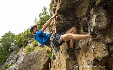 Een jonge klimmer hangt in de rotswand.