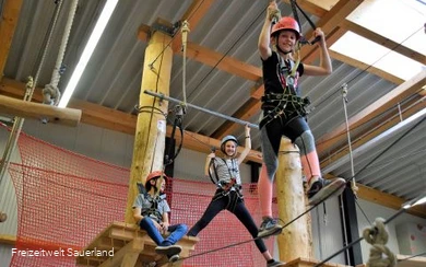 Kinder klettern im Indoor-Hochseilgarten.