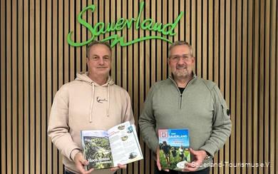 Jürgen Fischbach vom Sauerland-Tourismus und Pascal Möhrke vom Standpunkt-Verlag halten das fertige WAS IST WAS Buch in die Kamera.