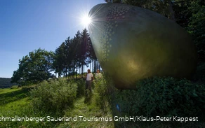 Two hikers at the "golden egg" on the Forest Sculpture Trail.