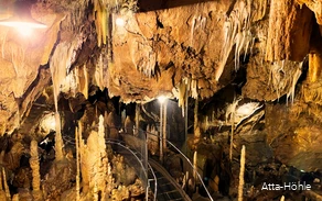 Einblick in die Atta-Höhle mit Stalaktiten und Stalakmiten und einem Gang, der zwischen ihnen durchführt.