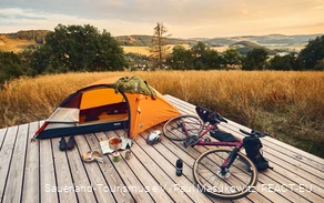 Grindfiets en tent op een trekkingplateau met uitzicht over het landschap van Sauerland