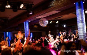 Eine gefüllte Tanzfläche im Willinger Brauhaus mit Diskokugel an der Decke und vielen tanzenden Menschen mit Armen in der Luft.