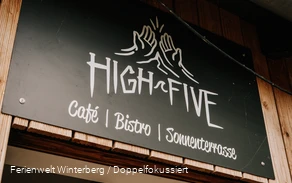 Ein Stück einer Eingangstür mit einem Schild mit der Aufschrift High Five oberhalb der Tür.