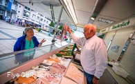 Fischhändler bietet einer Dame Tintenfisch an