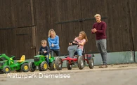 Kinder auf Spielzeugen auf dem Familienbauernhof Fass