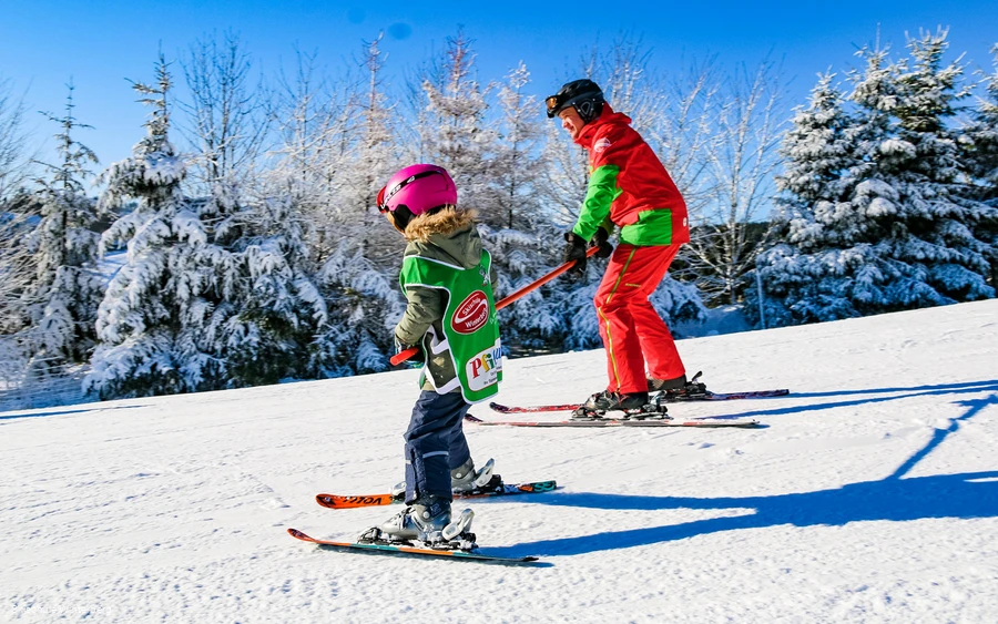 Skilehrer mit Kind beim Skifahren üben.