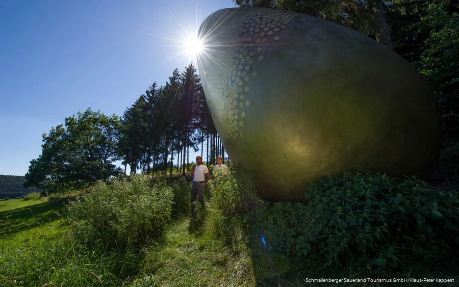 Twee wandelaars bij het "gouden ei" op het Forest Sculpture Trail.