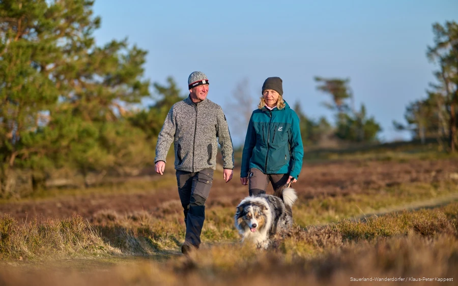 Een stel wandelt in de winter met hun hond over de Kahle Pön. De winterzon schijnt zachtjes.