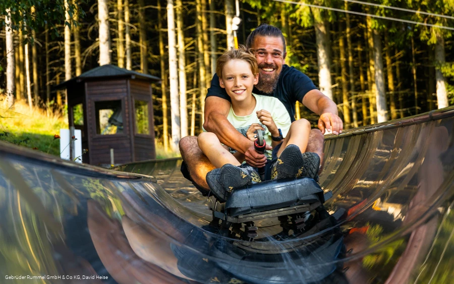 Mann und Mädchen auf der Sommerrodelbahn 