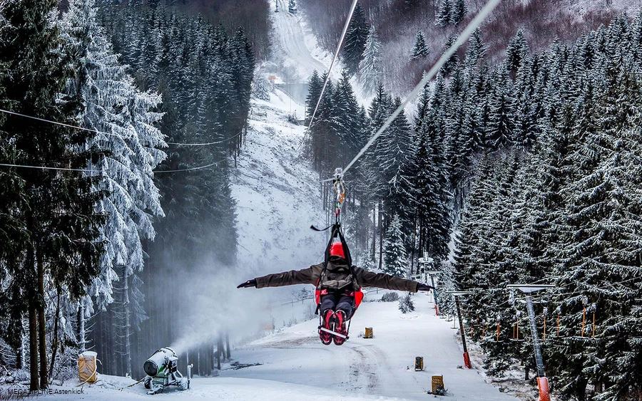 MEGAZIPLINE-Astenkick Ein Mann stürzt sich an der Megazipline hinab ins Tal.