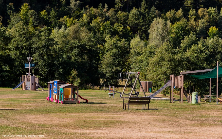 Spielplatz mit Eisenbahn, Schaukel, Rutsche und Klettermöglichkeiten.